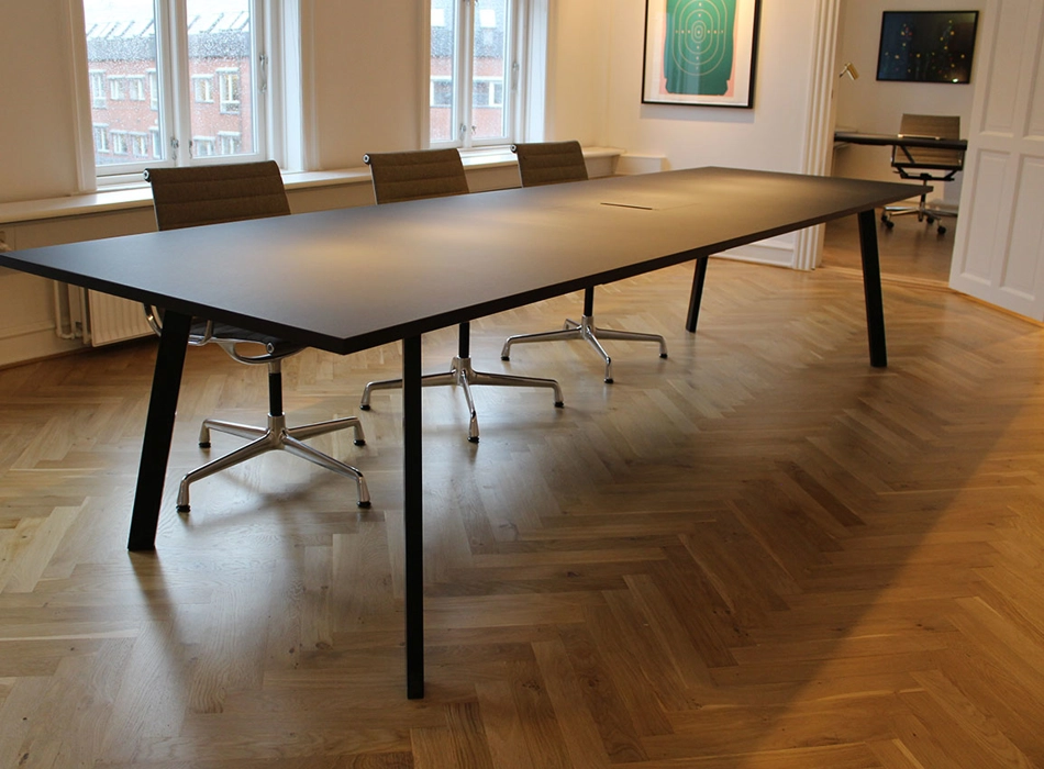 Mødebord udført i sort linoleum, men integreret kabelbrønd for tilslutning af pc, bordet er med sorte stålben.