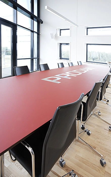 Mødebord med integreret logo, lavet med bordplade i linoleum og med  ilagt rustfri stål logo, understel med stålben.