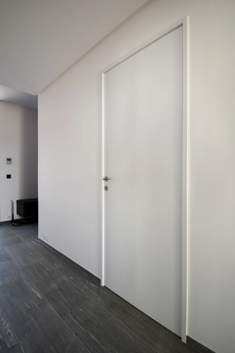 Moderne hvid dør snedkereret med smal karm med dørhåndtag og lås i rustfrit stål, traditionelle hvide døre