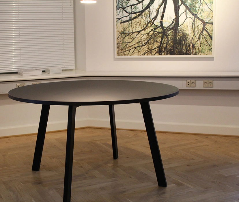 Rundt mødebord udført i sort linoleum, med ben i sort lakeret stål, mål efter ønske.